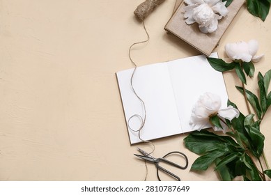Composition with blank book, threads, scissors and peony flowers on beige background, closeup