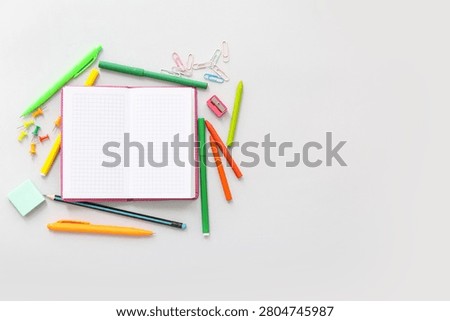 Composition with blank open notebook and colorful stationery on light background