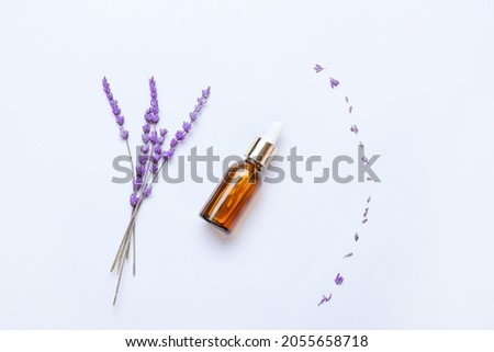 Composition with bottle of lavender essential oil and flowers on light background