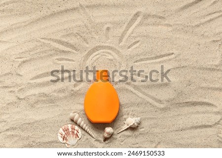 Composition with bottle of sunscreen cream, seashells and drawn sun on sand