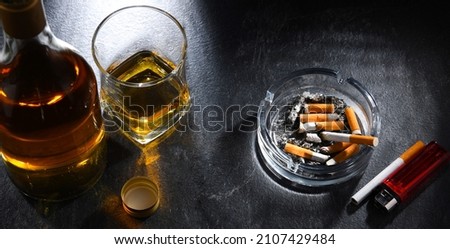 Composition with a bottle of whiskey, an ashtray and cigarettes.