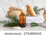Composition with bottles of essential oil, spa accessories and fir branches on light background