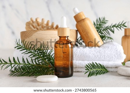 Composition with bottles of essential oil, spa accessories and fir branches on light background