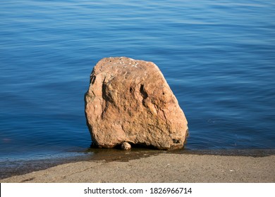 Composition from a boulder with a small stone on the shore of a reservoir