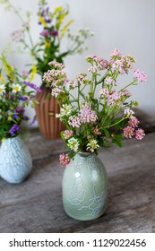 Composition from bouquets of summer wild flowers in vases on a wooden table, in rustic style. - Shutterstock ID 1129022456