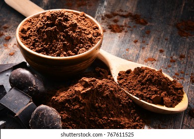 Composition with bowl of cocoa powder on wooden table.