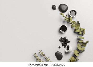 Composition With Bowls Of Activated Carbon Mask, Pills And Eucalyptus Branch On White Background