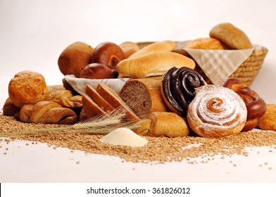 Composition with bread and rolls in wicker basket, combination of sweet pastries for bakery or market with wheat