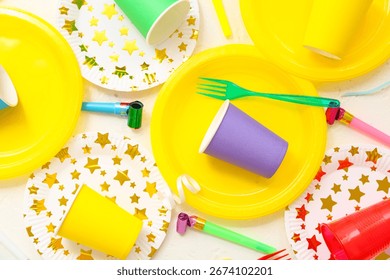 Composition with bright paper tableware and decor for birthday party on light background