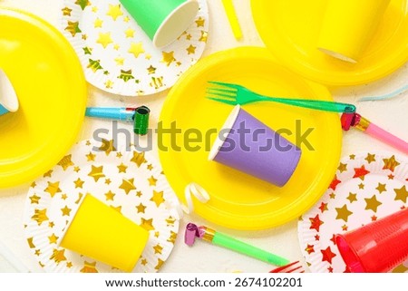 Composition with bright paper tableware and decor for birthday party on light background