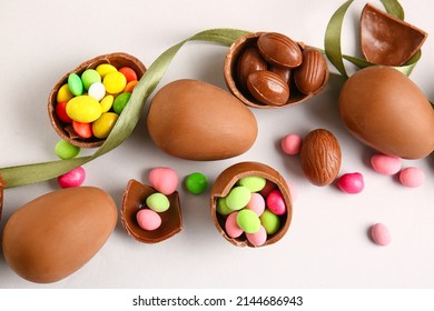 Composition with broken chocolate Easter eggs and different candies on light background