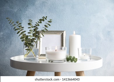 Composition with burning aromatic candles on table near color wall