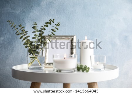 Composition with burning aromatic candles on table near color wall