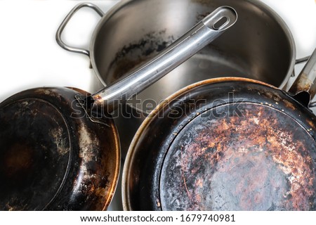A composition of burnt and dirty, stainless steel pots and pans on a white background. Isolated.
