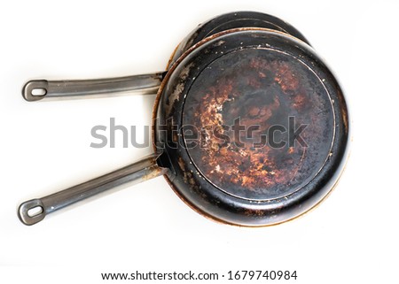 A composition of burnt and dirty, stainless steel pots and pans on a white background. Isolated.