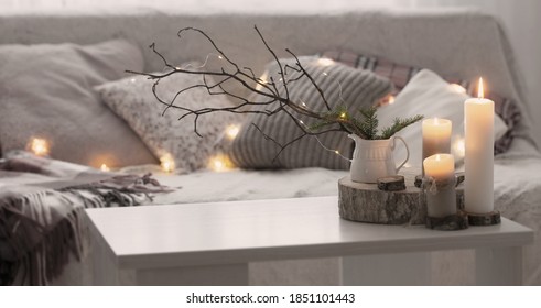 Composition of candles on  white table against the background of  sofa with plaids and pillows. Cozy home concept - Powered by Shutterstock