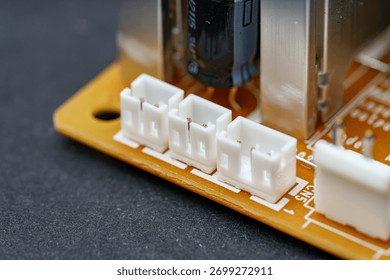 The composition captures three white, square connectors in a row on an orange printed circuit board. These are components in electronics, showcasing intricate engineering.