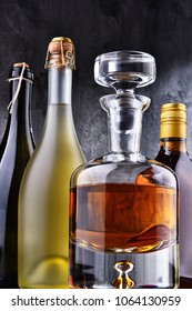 Composition with carafe and bottles of assorted alcoholic beverages.