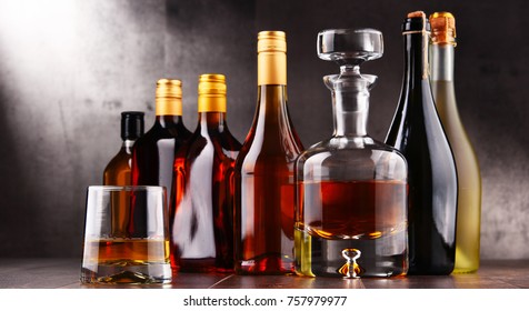 Composition with carafe and bottles of assorted alcoholic beverages.