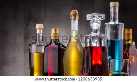 Composition with carafe and bottles of assorted alcoholic beverages.