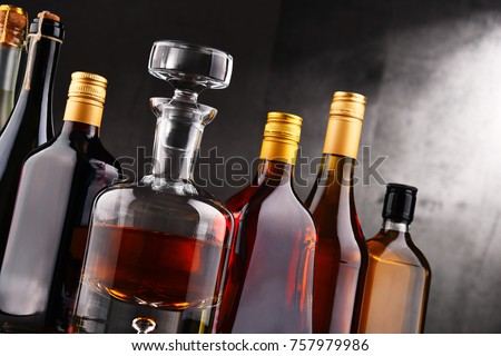Composition with carafe and bottles of assorted alcoholic beverages.