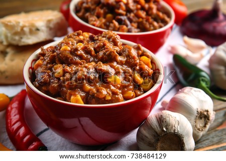 Composition with chili con carne in bowls on table