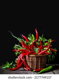 Composition of chili peppers and spicy fresh herbs. Chili peppers and greens in a wicker basket on a wooden table close-up. Aesthetics, art.Edible composition. - Shutterstock ID 2177749137