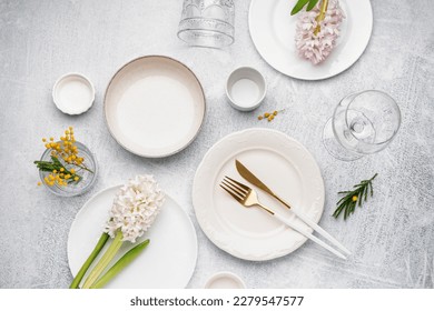 Composition with clean dishes, cutlery and beautiful flowers on grey grunge background - Powered by Shutterstock