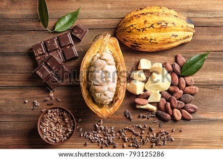 Composition with cocoa pod and products on wooden background, top view