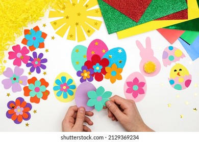 Composition of colorful Easter eggs, flowers, sun, chicken, rabbit from multi-colored paper, step by step. Child makes crafts his own hands. Easter DIY handmade art creativity. Top view, copy space