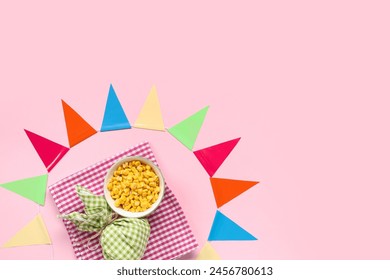 Composition with colorful flags, corn and bundle bag for Festa Junina celebration on pink background