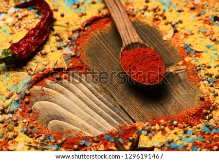 Composition of condiment making heart shape. Food art concept. Wood spoon with paprika, red chili pepper, anise star, sea salt and scattered seasoning. Set of spices on wooden background.