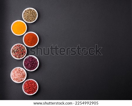 Composition consisting of a variation of several types of spices in white ceramic bowls on a textured concrete background