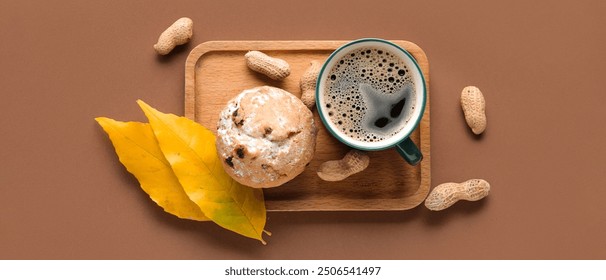 Composition with cup of aromatic coffee, muffin, autumn leaves and peanuts on brown background