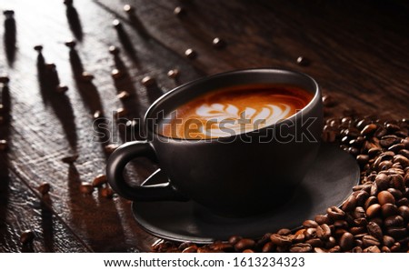 Composition with cup of caffe latte and coffee beans.