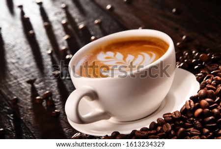Composition with cup of caffe latte and coffee beans.