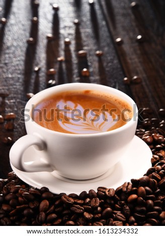 Composition with cup of caffe latte and coffee beans.