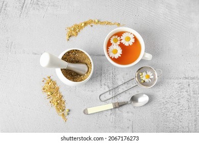 Composition with cup of chamomile tea and dried flowers on light background