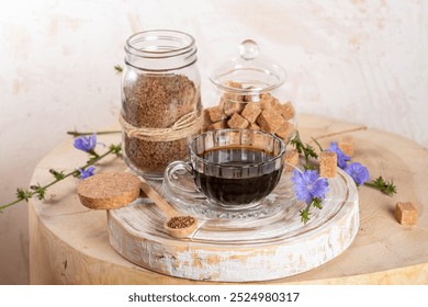 Composition of cup chicory beverage, jars of granulated soluble chicory and cane sugar, spoon on wooden stump. Chicory is decaf drink healthy emotional overload, improves sleep, good for digestion.