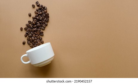 Composition With A Cup And Coffee Beans On A Plain Brown Background With Space For Text