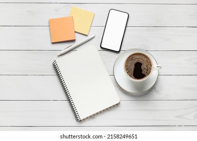 Composition With Cup Of Coffee, Notebook, Sticky Notes And Mobile Phone On White Wooden Background