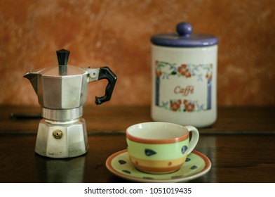 composition with a cup of coffee and what is needed to prepare coffee in the traditional way, on an antique wooden piece of furniture in natural light