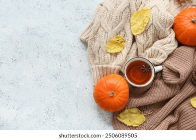 Composition with cup of tea, warm sweaters, pumpkins and autumn leaves on light background - Powered by Shutterstock