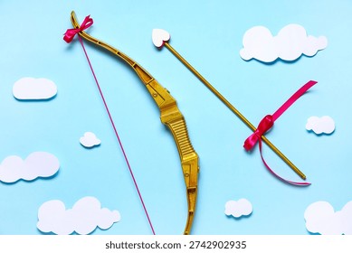 Composition with cupid's bow, arrow and paper clouds on blue background. Valentine's Day celebration