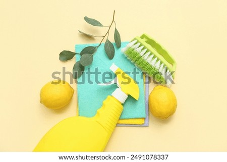 Composition with detergent, dusters, lemons and cleaning brush on color background