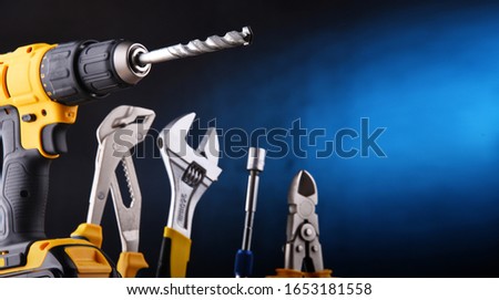Composition with different kinds of hardware tools including cordless drill, monkey spanner and screwdriver