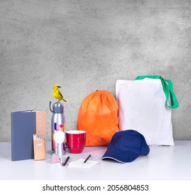 Composition of different promo products rich colors -Thermo mug-pens-mug-notebook-cap-notepaper-Backpack-tote bag canvas -exotic bird. - Shutterstock ID 2056804853