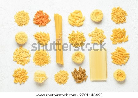Composition with different tasty uncooked pasta on light background