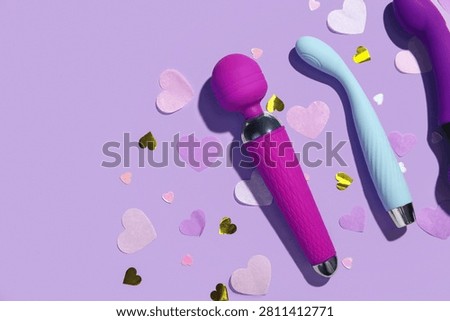 Composition with different vibrators and confetti on lilac background