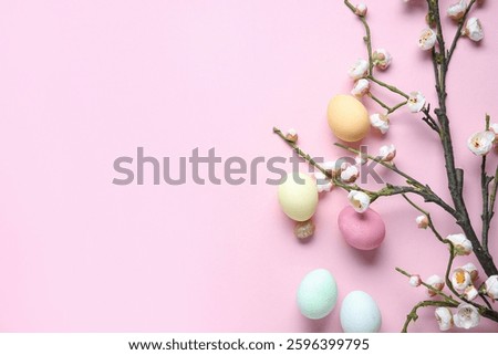 Composition with Easter eggs and blooming tree branches on pink background